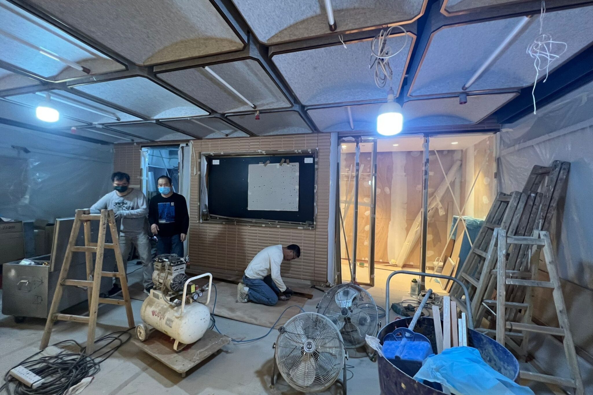 Several professional workers inside a workshop, busy with maintenance work as part of a redevelopment project by Studio X