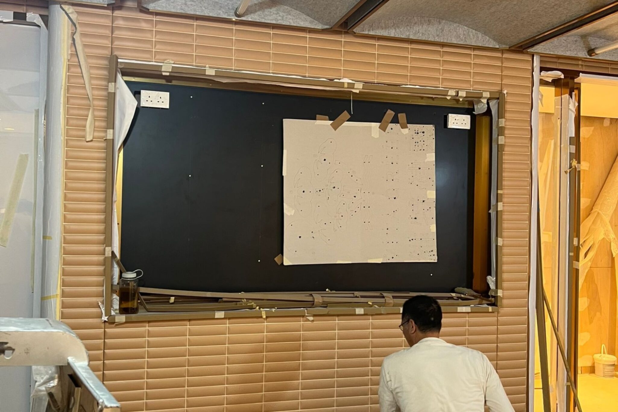 A professional looking up at the PVC false wall design inside a workshop undergoing maintenance by Studio X